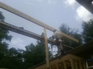 Carpenter setting a ridge beam over a new addition frame — Ice Dam Removal by Roofing Brothers in Heron
