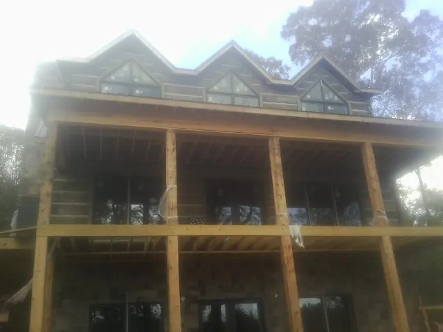 Dormers and porch framing on a large log home under construction — Roof Coating work by our crew in Heron