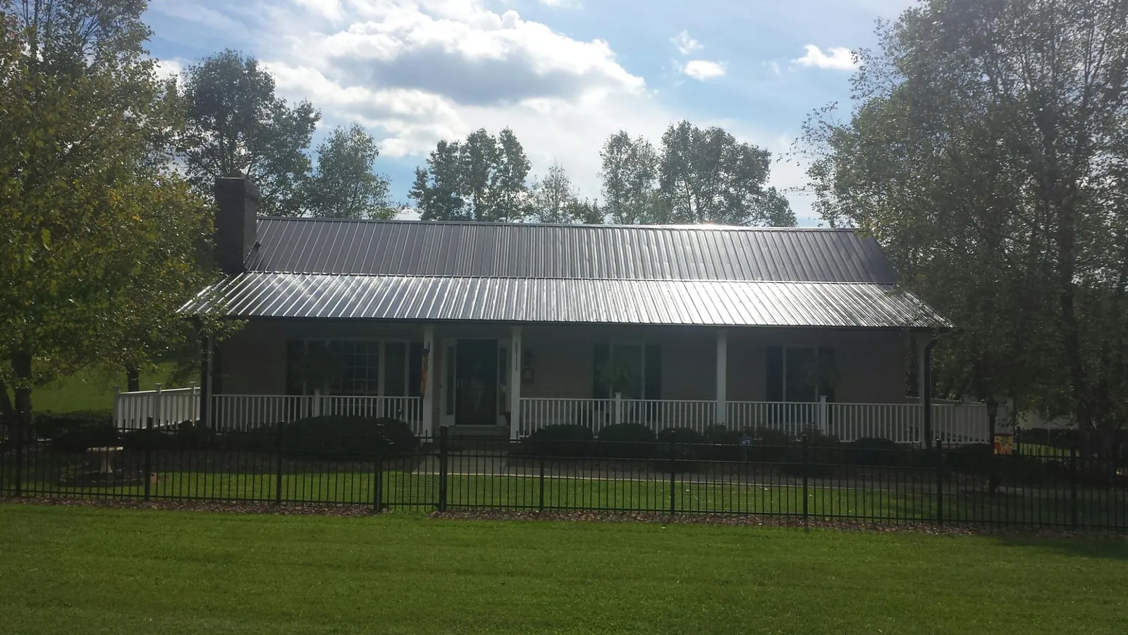 Gray metal roof on a brick ranch with a full width front porch — Gutter Guard Installation work by our crew in Heron