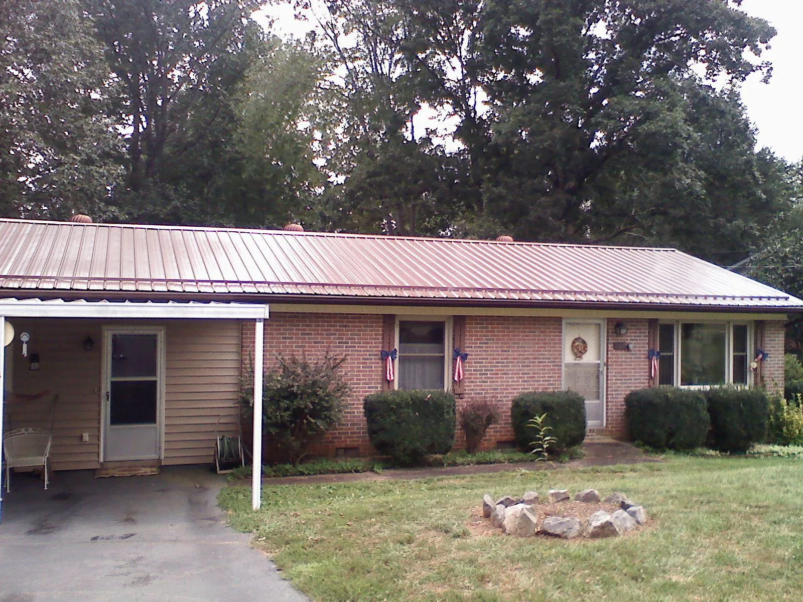 Bronze metal roof and carport on a brick ranch home — Roof Repair work by our crew in Heron