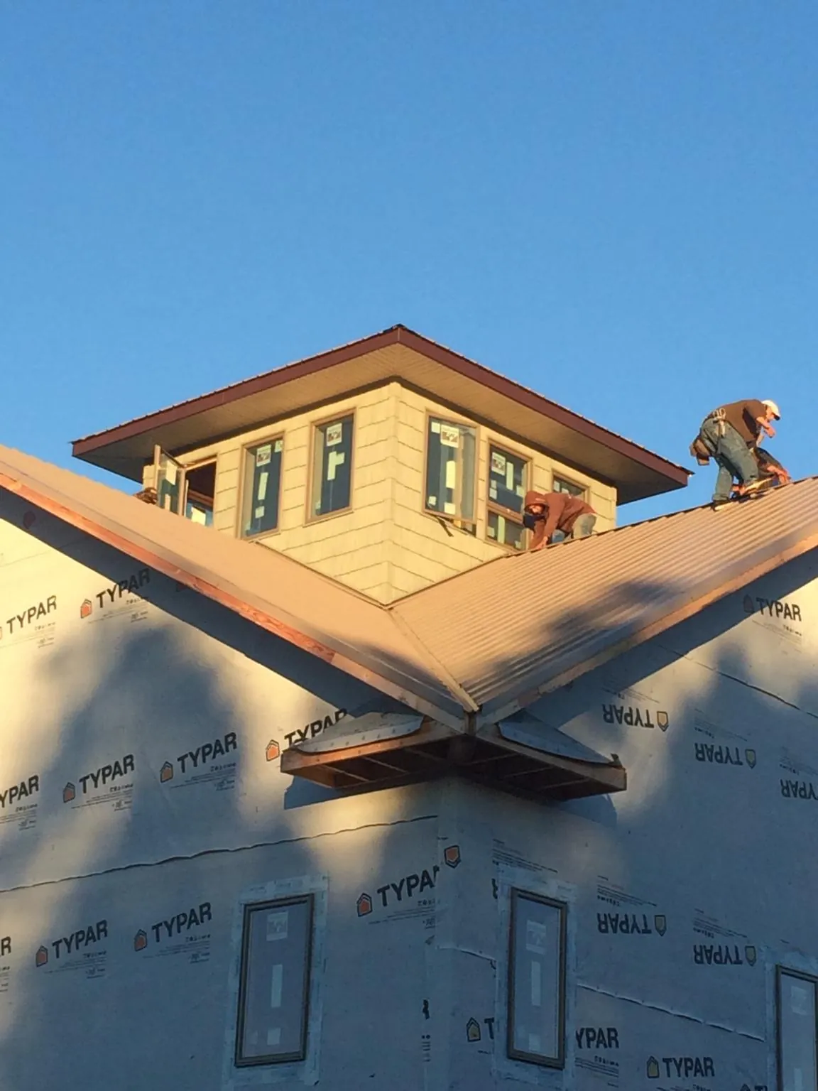 Roofers working around a rooftop cupola on a new metal roof at sunset — Roof Waterproofing in Heron by Roofing Brothers